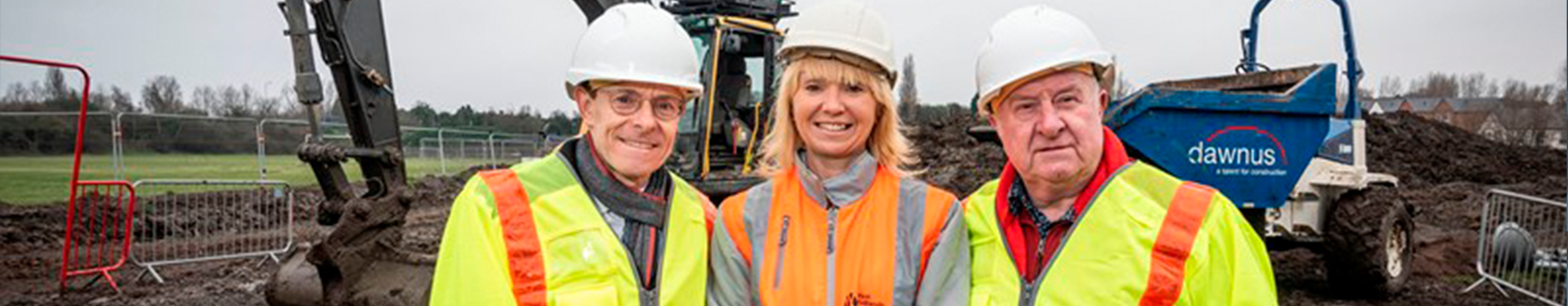 Two men and a woman in high vis and hard hats at construction site