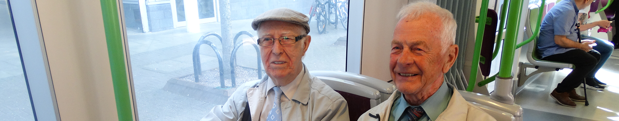Two elderly men on smiling, sitting on the tram